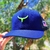 Boné masculino azul marinho com detalhe em verde e logo de chifre na parte frontal.