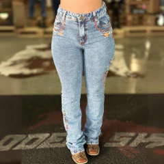 Calça feminina de jeans com detalhes bordados, modelo Texas Farm Vitality Umber, em ambiente de loja.