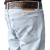 Detalhe do bolso traseiro da calça Wrangler masculina Lycra Regular em jeans claro, com cinto marrom trabalhado.