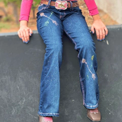 Calça jeans infantil feminina azul com bordados florais coloridos, usada com cinto marrom e camisa rosa