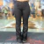 Calça feminina preta estilo tradicional, com corte reto e detalhes de botão, usada por modelo em ambiente rústico.