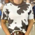 T-Shirt feminina com estampa de vaca em preto e branco e gola marrom