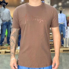 Camiseta masculina marrom com estampa da marca Tatanka na parte frontal, usada por modelo com tatuagem no braço direito.