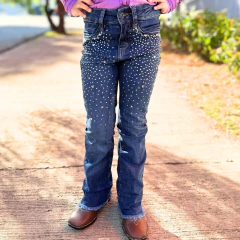 Calça infantil feminina jeans azul escuro com detalhes de strass em forma de estrelas e corações, usada por criança em ambiente externo