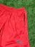 Short de color rojo de marca Puma, con detalles en negro y una textura suave, sobre fondo de césped artificial.