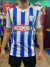 Camiseta retro de Racing Club con rayas verticales azul y blanca, y logo de Rosamonte en el centro.