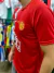 Camiseta retro de Manchester United en color rojo, con el escudo del club y el nombre "Cristiano Ronaldo" en la parte delantera, vista de perfil.
