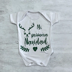 Body de bebé blanco con diseño navideño que dice "Mi primera Navidad" y tiene un ciervo con astas.