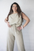 Modelo luciendo una blusa de lino color beige, con pantalones a juego y un peinado natural, posando con una mano en la cintura.