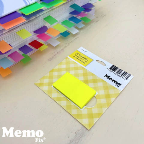 Banderitas adhesivas amarillas MemoFix de 24x45mm en paquete de 50 hojas sobre una superficie clara, junto a un libro con separadores de colores