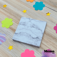 Notas adhesivas MemoFix M con diseño de mármol blanco, 74x74mm, sobre una superficie de madera con decoraciones coloridas.