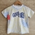 Remera blanca de niño con estampado tie-dye en tonos amarillos y azules, con la frase "GOOD VIBES" 