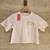 Remera de color rosa claro con el texto "selflove CLUB" en verde