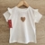 Remera blanca con volados, estampado de corazón dorado