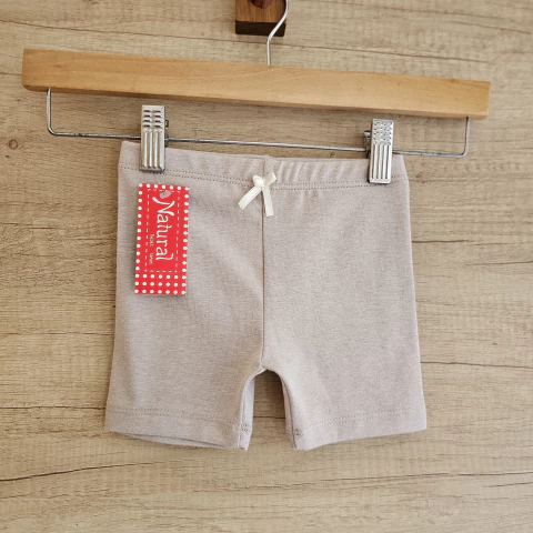 Calza corta beige , con lazo blanco en la cintura.
