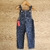 Jardín de denim para bebés y niños, con tirantes y un bolsillo frontal.