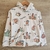 Campera blanca con de plush estampado de capibaras y dibujos coloridos