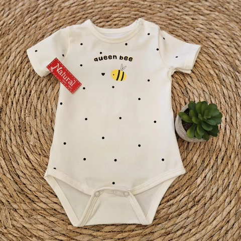 Body de bebé color blanco con estampado de puntos negros y diseño de una abeja amarilla con texto "queen bee".