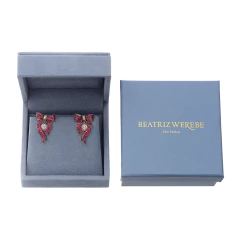 Brinco Beatriz Werebe em caixa, com detalhes em pedras coloridas e laços.