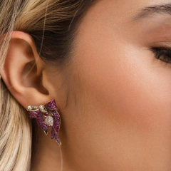 Brinco feminino Beatriz Werebe em formato de laço com pedras vermelhas e detalhes em prata, usado na orelha de mulher