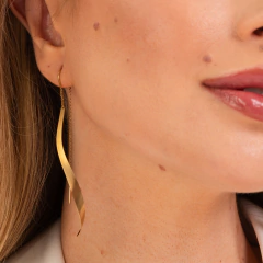 Brincos longos dourados H. Stern My Collection adornando a orelha de uma mulher.