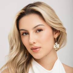 Mulher loira usando brinco H. Stern nó búdico DVF em tom dourado