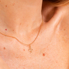 Colar de ouro da Vivara com crucifixo, exibido em um pescoço feminino.