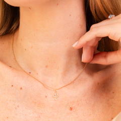 Colar de ouro Vivara com crucifixo, exibido em um pescoço feminino.