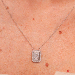 Escapulário Elisabete Gaspar em colar prateado, com detalhe em relevo e pedras ao redor.