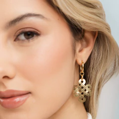 Brinco H. Stern nó búdico DVF em metal dourado com acabamento martelado, usado em orelha feminina