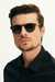 Homem usando óculos de sol redondo Duna Tortoise Havana com armação marrom e lentes escuras.