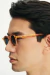 Close-up of a person wearing round amber sunglasses.