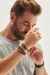 Pulseira masculina de couro marrom com fecho magnético prata no pulso de um homem.