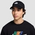 Jovem usando boné preto da Nike, com detalhe em bordado na frente, e camiseta preta com logo colorido.