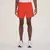 Homem usando shorts laranja da New Balance, modelo Sport Essentials 2 em 1, em pé com tênis brancos.