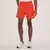 Homem usando bermuda esportiva laranja da New Balance com tênis brancos.