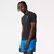 Homem usando camiseta New Balance Impact Run preta, com short azul, posando para foto em fundo claro.