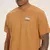 Camiseta New Balance 550 com bordado, na cor marrom, exibindo um desenho de tênis no peito.