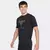Homem sorridente vestindo uma camiseta preta da Under Armour com a estampa "Project Rock".
