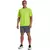 Homem usando camiseta verde neon da Under Armour Tiger Tech 2.0, com calções cinza e tênis brancos.