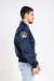 homem vestindo jaqueta bomber azul marinho com bolsos frontais e patches da NASA e das missões Apollo