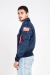 homem vestindo jaqueta bomber azul marinho com bolsos frontais e patches da NASA e das missões Apollo