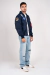 Modelo usando jaqueta bomber na cor azul com detalhes bordados da NASA, calça jeans e tênis casual branco