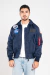 homem vestindo jaqueta bomber azul marinho com bolsos frontais e patches da NASA e das missões Apollo