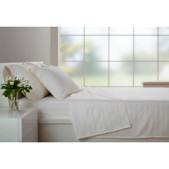 Jogo de lençol solteiro king em tom marfim, com três peças de algodão egípcio 400 fios percal, arrumado em cama branca com duas almofadas e vaso de flores ao lado