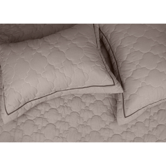 Cobre leito solteiro matelado em tom fendi com detalhes em chianti, acompanhado de duas fronhas.