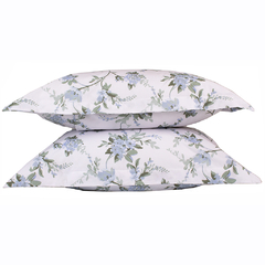 Conjunto de fronhas estampadas em fundo branco com flores azuis e verdes, parte do jogo de lençol queen Smeraldini Milano.