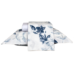 Conjunto de cama com estampa de folhas em tons de azul sobre fundo branco, incluindo travesseiros e lençol.