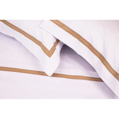 Conjunto de lençóis brancos com detalhes em marrom, incluindo fronhas e lençol de cama.