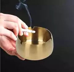 Cenicero de acero inoxidable con acabado dorado, dimensiones 9.5cm de diámetro y 5cm de alto. Diseño elegante y lujoso, fácil de limpiar y resistente. Ideal para uso en interiores y exteriores.